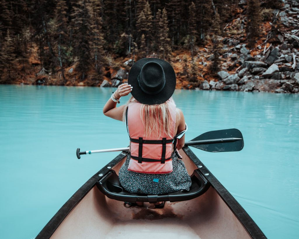 A woman sitting on the boat while wearing a black hat