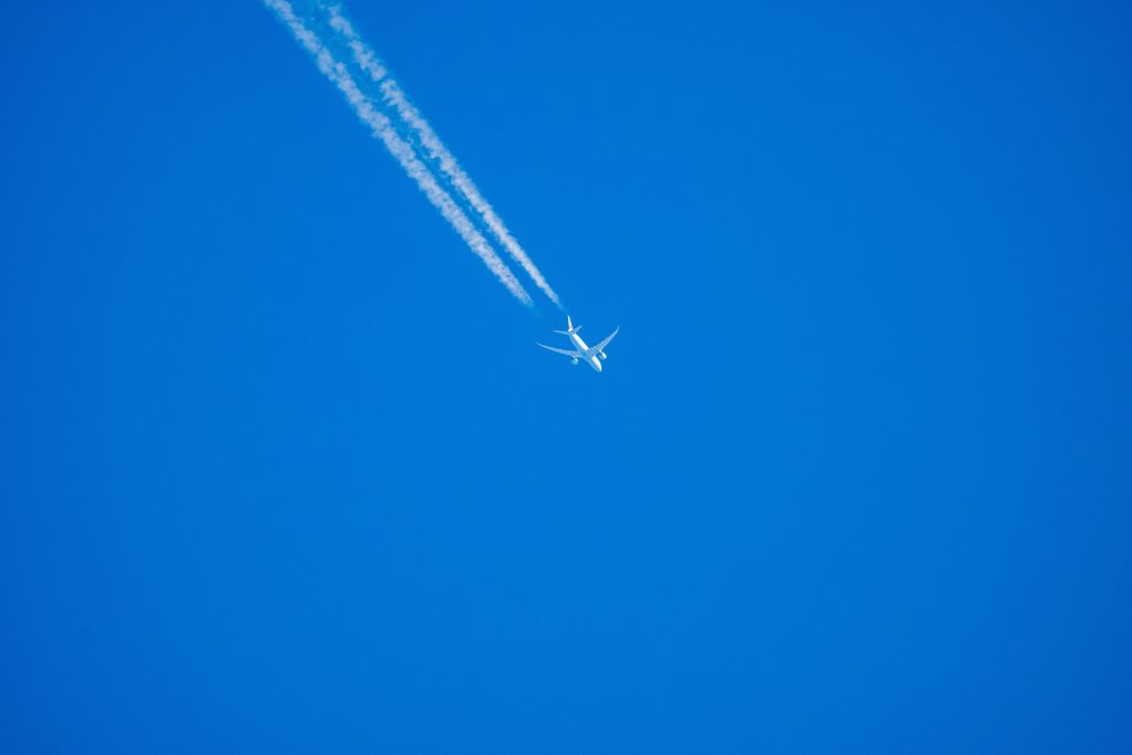 Low angle shot of an airplane flying in the clear blue sky