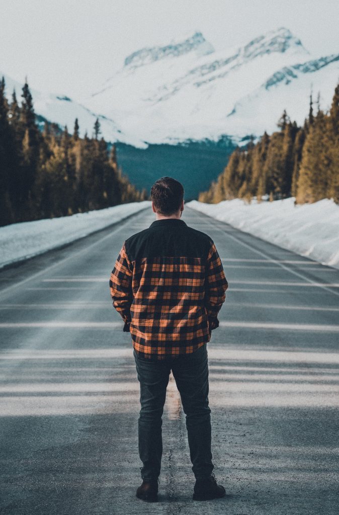 Man in black and orange plaid jacket standing on road