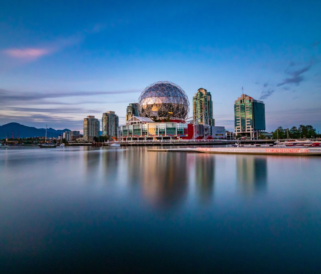 Modern skyscrapers and spherical construction on seafront at daytime