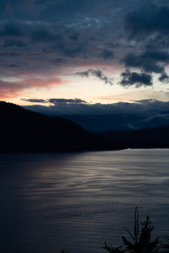 Silhouette of mountain near body of water under dark clouds